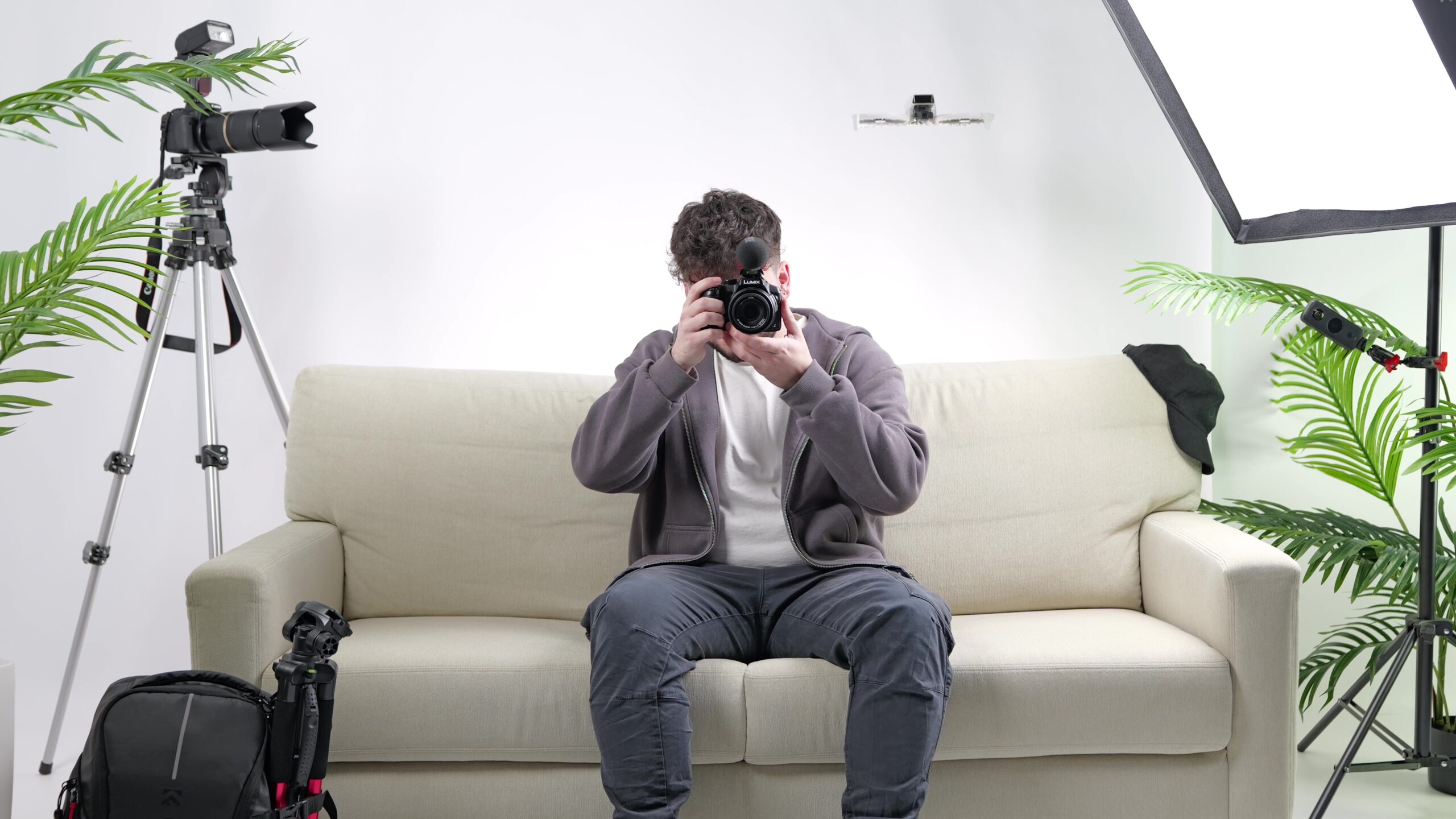 Valentin Witt sitzt mit einer Kamera auf einer Couch im Studio