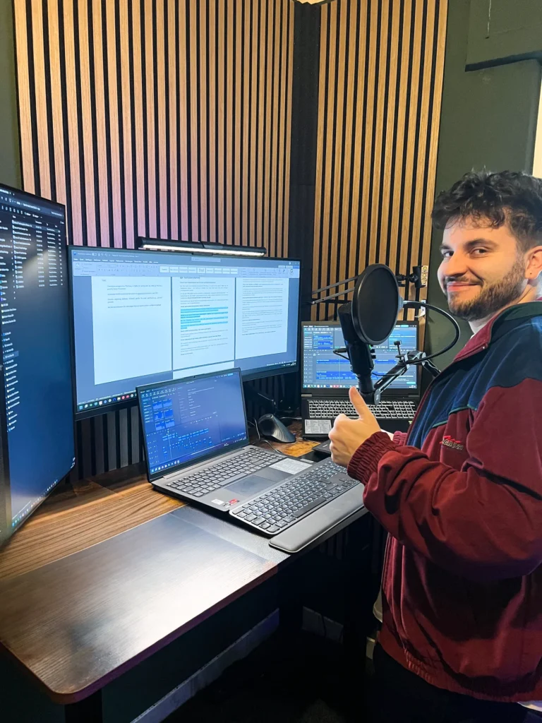 Valentin Witt am Aufnahmeplatz mit Mikrofon, mehreren Monitoren und Audioprojekten